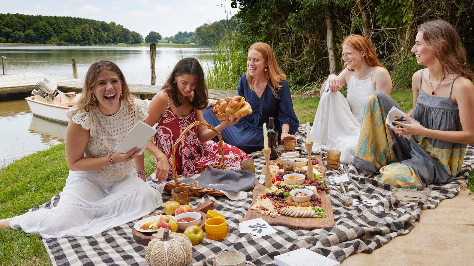 Group of 5 women gather around picnic to celebrate Shabbat with fall festive colors and foods