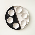 handmade black and white ceramic passover seder plate with six sections on a contemporary table setting